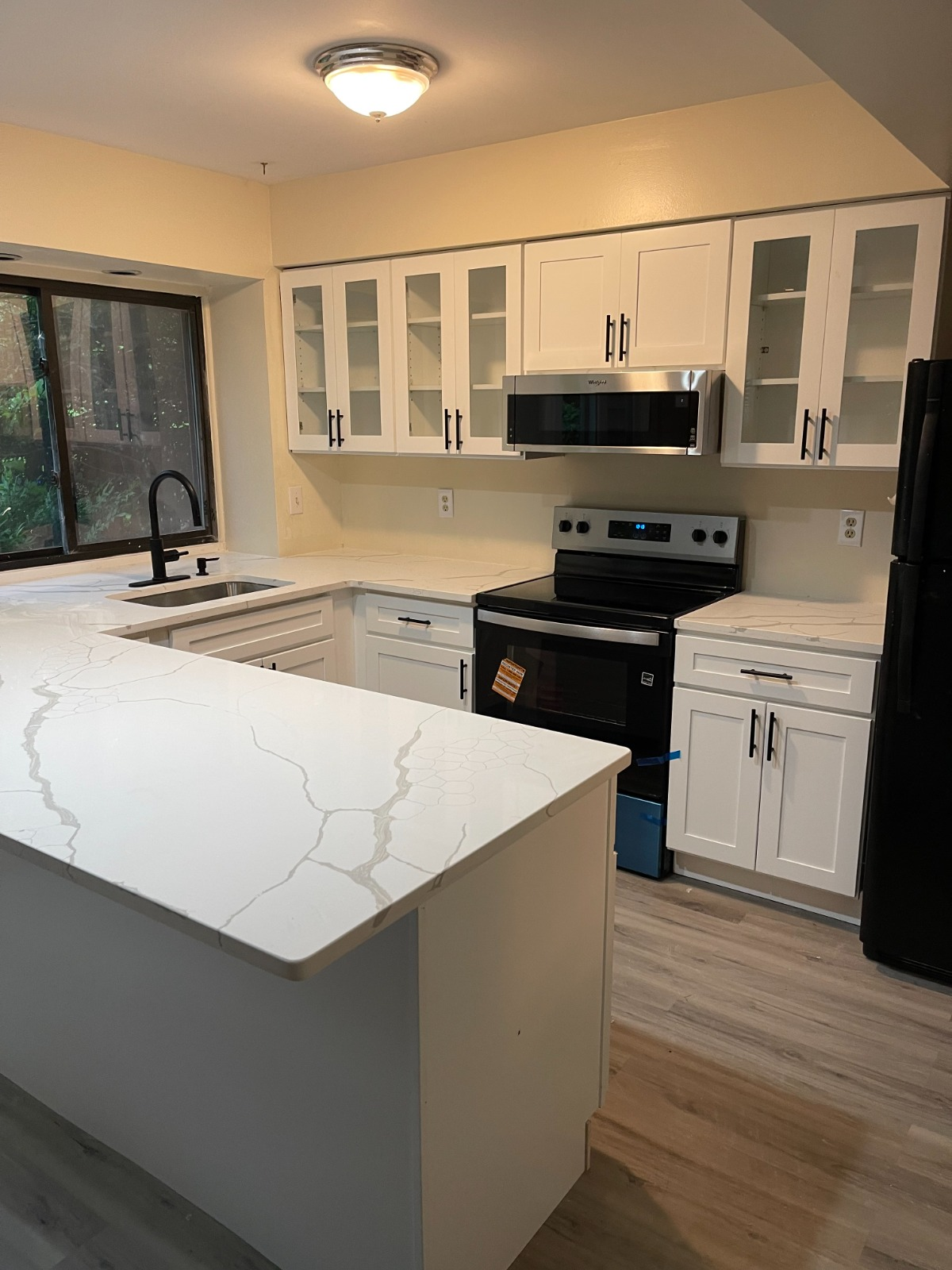 Bright modern kitchen remodel with white shaker cabinets, marble countertops, and stainless appliances