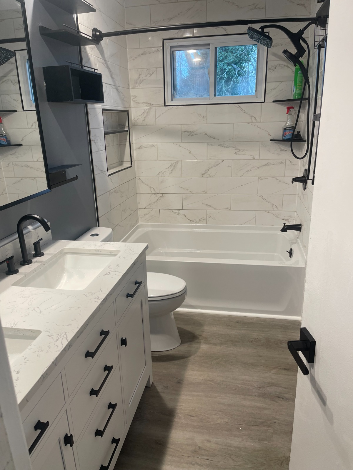 Bathroom remodel with marble tile surround, quartz vanity, and matte black fixtures