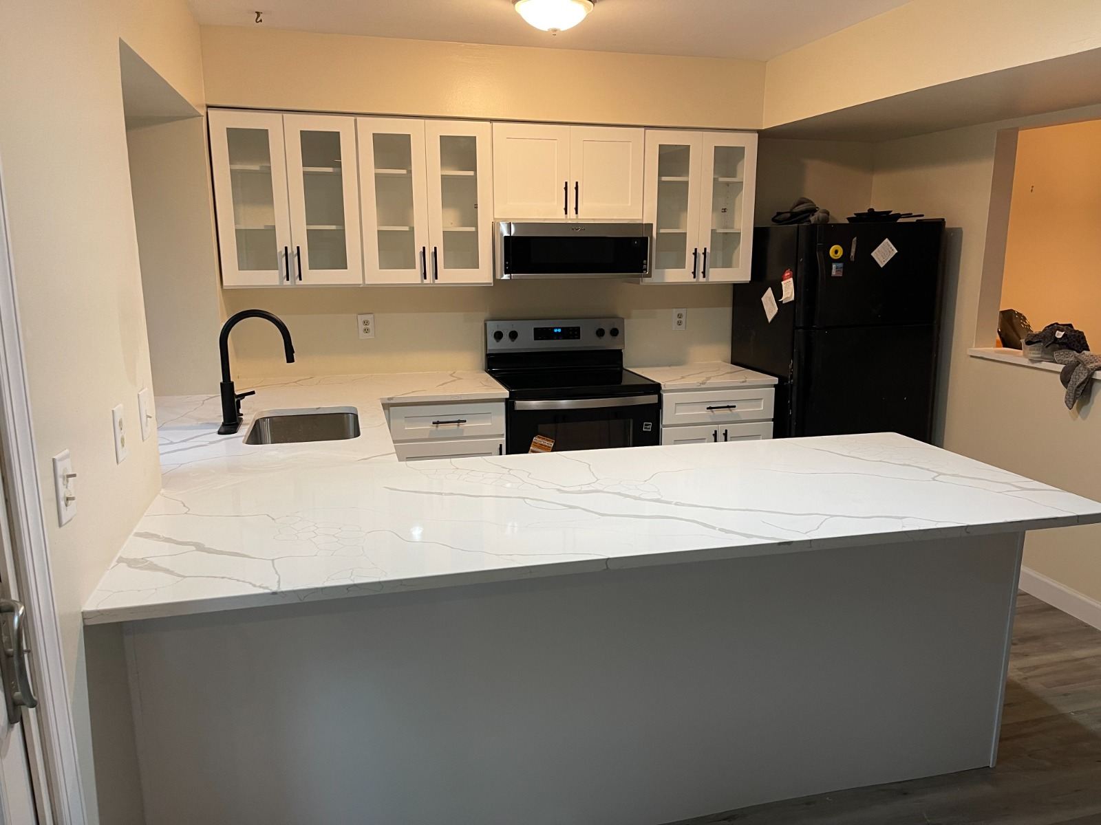 Kitchen remodel with white shaker cabinets, quartz waterfall island, and matte black fixtures